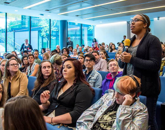 Person stands with microphone in audience