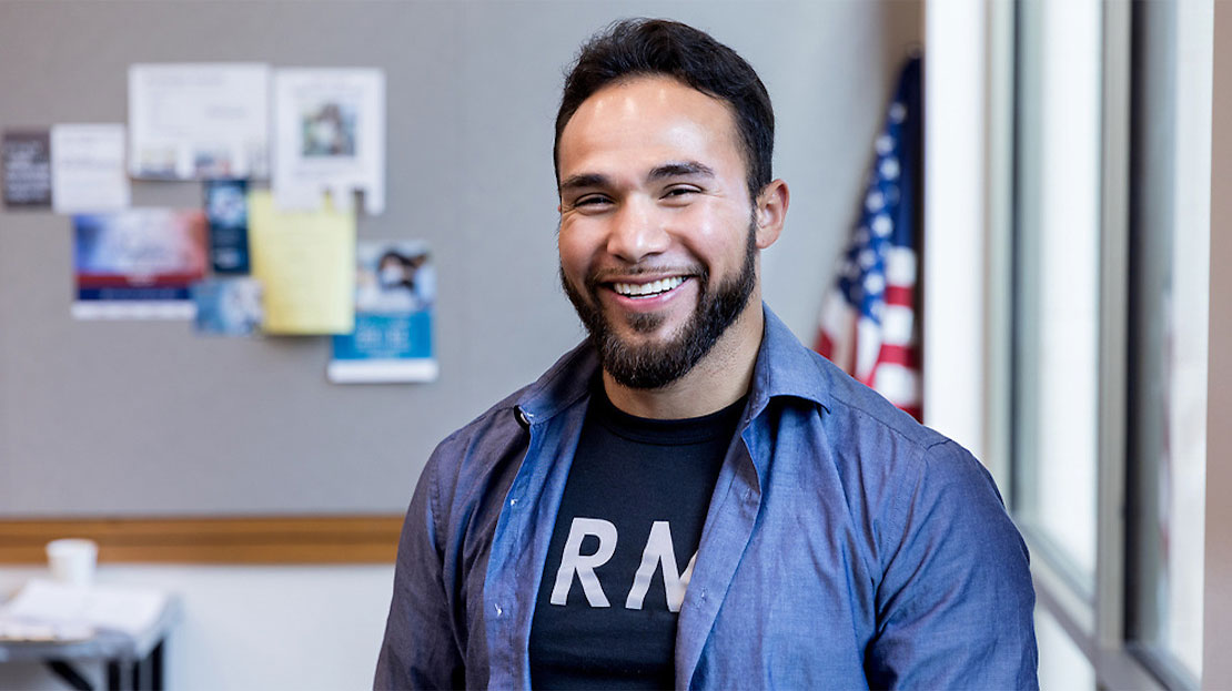 Student smiling with U.S. flag in background
