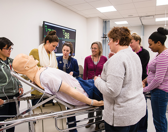 Students work on a practice body on a gurney