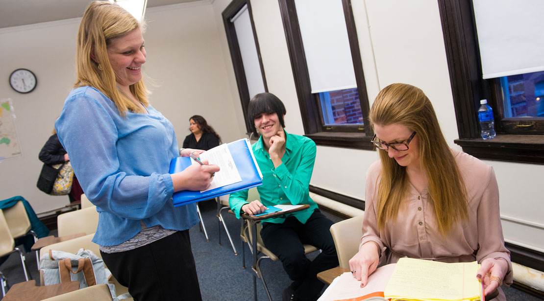 Students in class in a discussion, while smiling.