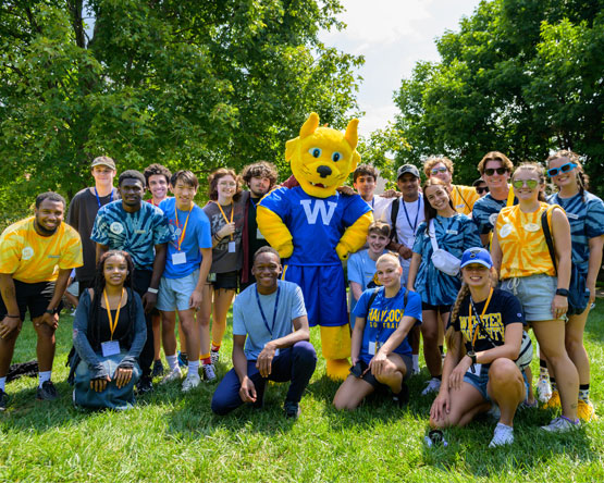 A large group of Webster students gather for a photo with the Gorlok mascot on the quad.